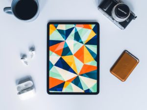 iPad, multi colored iphone case beside camera lens and camera lens